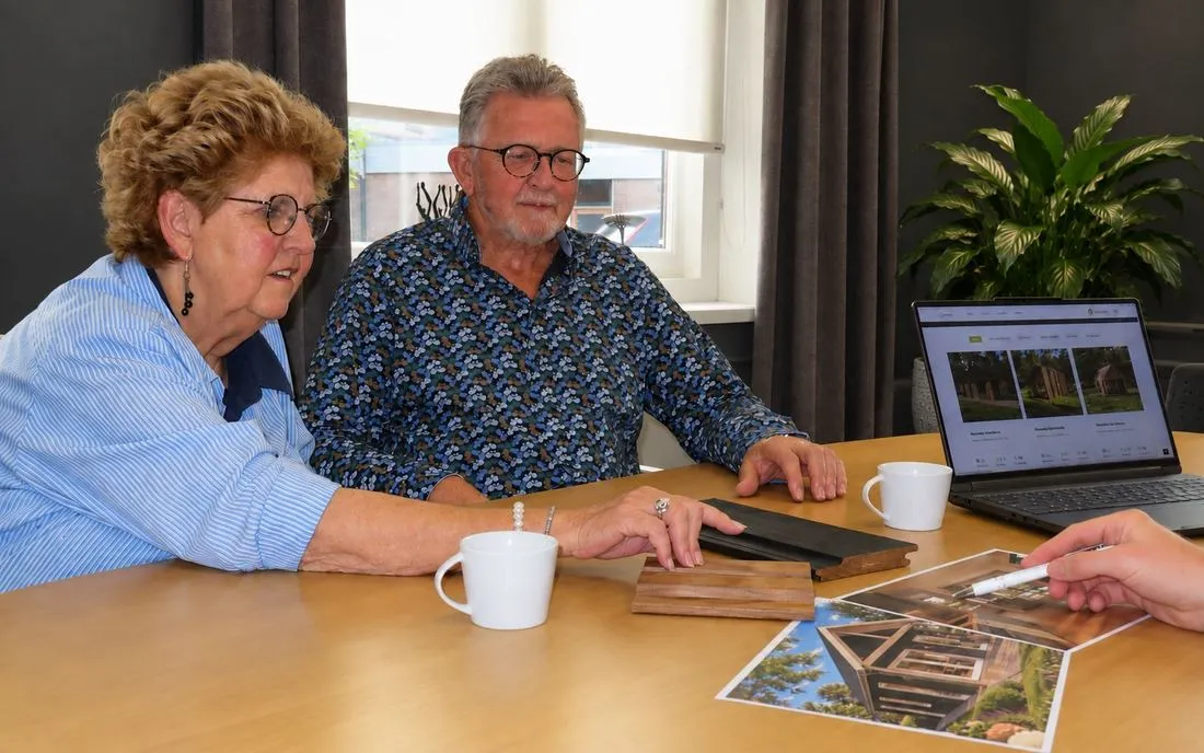 Een echtpaar bespreekt hun woonwensen aan tafel met een adviseur